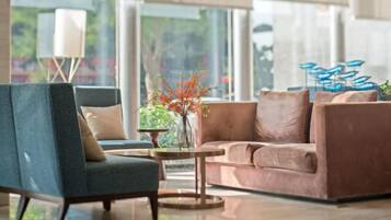 A modern living room with a blue armchair, a brown sofa, and a coffee table with a vase of flowers.