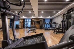 Ein Fitnessraum mit Trainingsgeräten, Laufband und einer Gewichtbank.