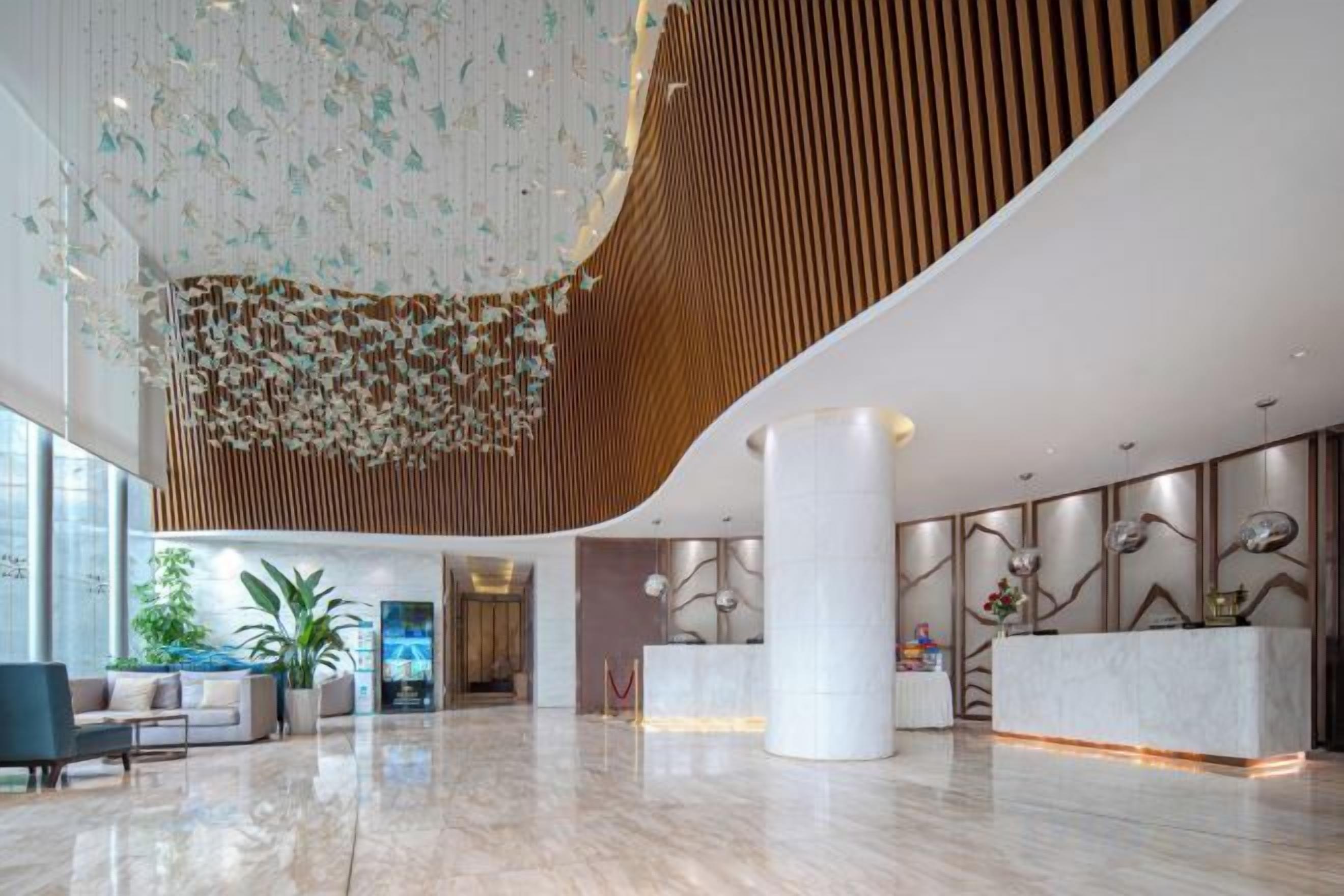 A spacious lobby with a high ceiling, a reception desk, and a large plant.
