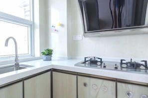 Cozinha com pia, fogão, armários e janela.