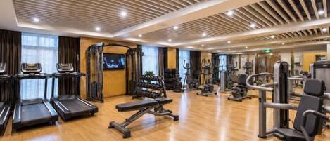 Academia com esteiras, aparelhos de musculação e espelho.