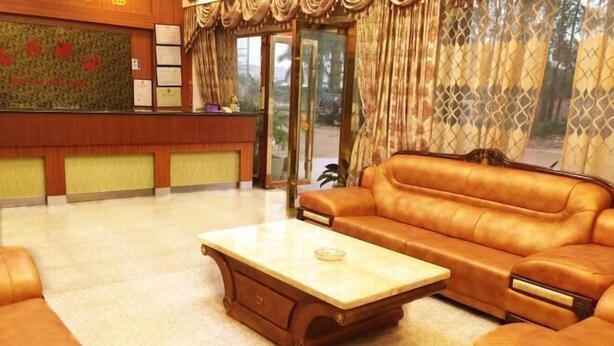 A lobby with a reception desk, a sofa, and a coffee table. - Baile Hotel (Enping)