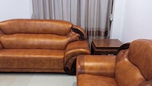 A brown leather sofa set in a room with a tiled floor and a curtain in the background. - Baile Hotel (Enping)