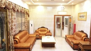 A living room with a sofa set, a coffee table, and a wooden side table. - Baile Hotel (Enping)