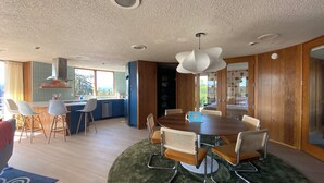 A modern kitchen with a dining area, wooden cabinets, and a large window. - Newly renovated penthouse getaway! (Eugene)