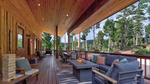 Eine überdachte Holzterrasse mit Sitzbereichen und einer Feuerstelle.
