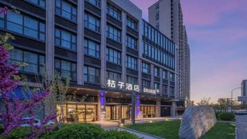 A hotel with a modern facade, large windows, and a well-maintained outdoor area with a rock and greenery.