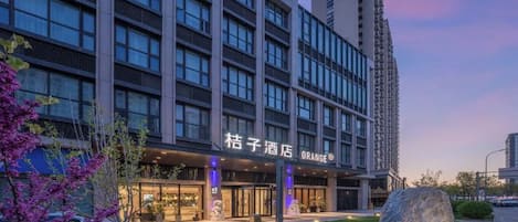 Un hôtel doté d’une façade moderne, de grandes fenêtres et d’un espace extérieur bien entretenu, agrémenté de rochers et de verdure.