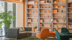 A modern living room with a sofa, chairs, a bookshelf, and a potted plant. - Orange Hotel (Beijing Daxing Biomedical Base Longhu Tianjie Branch) (Beijing)