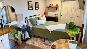 A bedroom with a bed, bedside table, lamp, and a potted plant. - Adorable Casita with Pool for 2 People (Tubac)