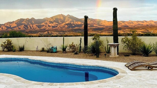 A swimming pool with a view of mountains and a rainbow. - Adorable Casita with Pool for 2 People (Tubac)