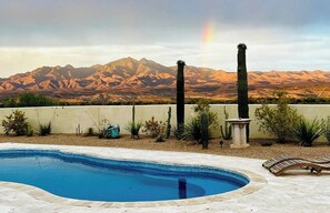 Una piscina con vistas a montañas y un arcoíris.