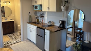 A compact kitchen with white cabinets, a microwave, a coffee maker, and a sink. - Adorable Casita with Pool for 2 People (Tubac)