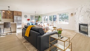 En moderne stue med en sort lædersofa, et glasbord og en pejs.