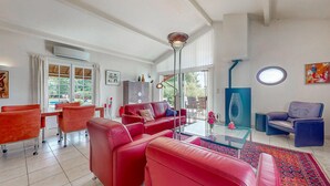 Una sala de estar moderna con sofás rojos, una mesa de centro de vidrio y un sillón azul.