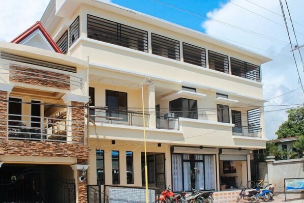 A two-story residential building with balconies, a garage, and a visible motorcycle.