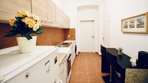 Een keuken met witte kastjes, een fornuis en een spoelbak. Op het aanrecht staat een vaas met bloemen.