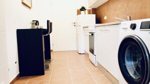 Een functionele keuken met een wasmachine, een koelkast en een eethoekje.