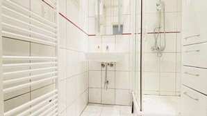Un baño moderno con un lavamanos blanco, cabina de ducha de vidrio y ducha a ras de suelo.