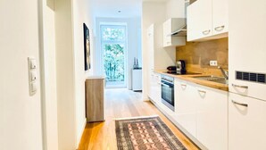 Una cocina moderna con armarios blancos, encimera de madera y horno empotrado.