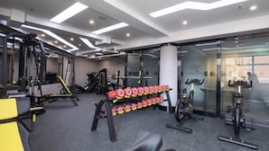 Un gimnasio moderno con diversos equipos de ejercicio, como mancuernas, una banca y máquinas de cardio.