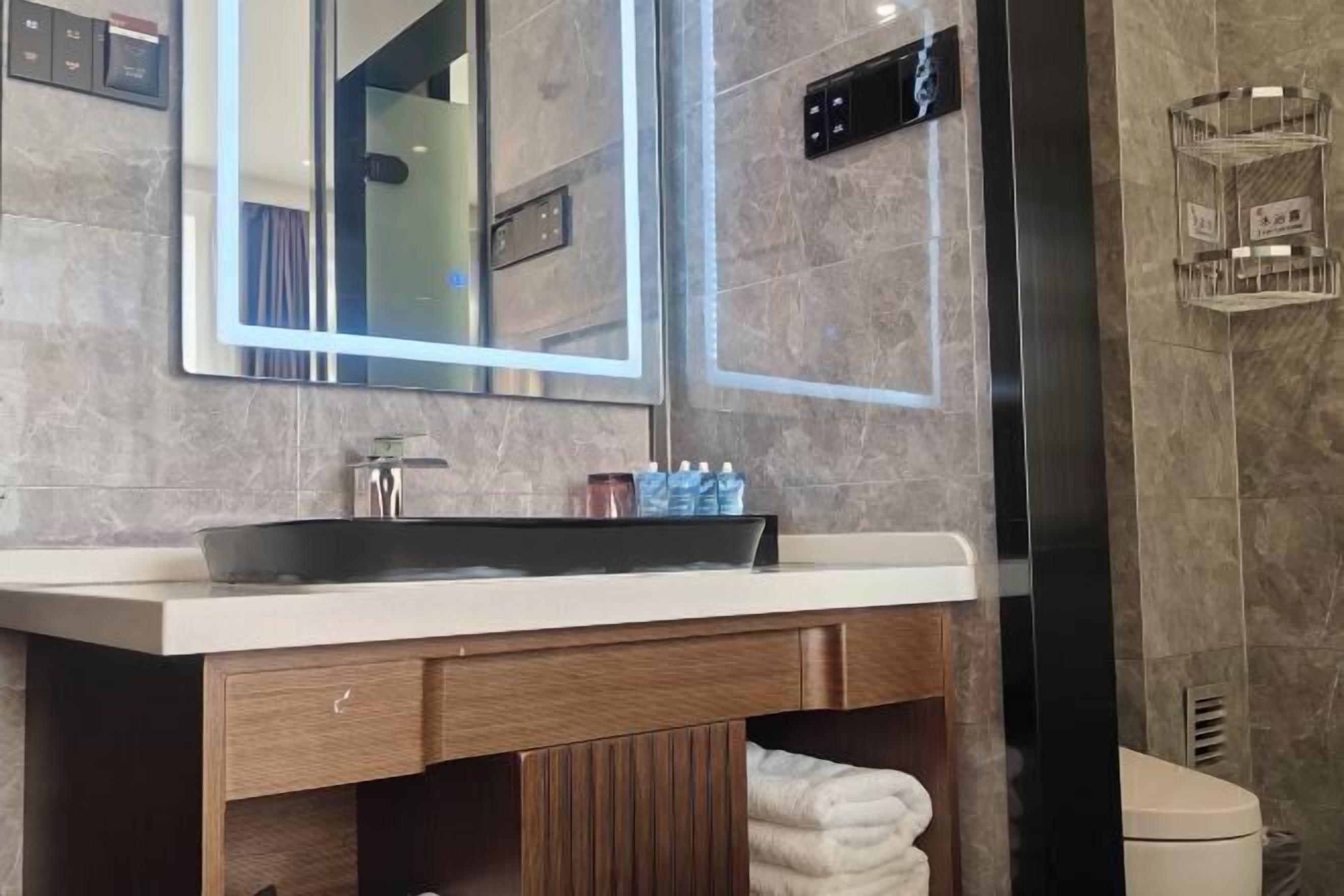 Un baño moderno con un espejo grande, un lavamanos y un inodoro.