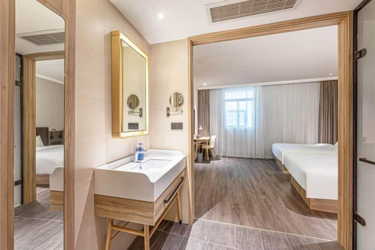 Una camera d'albergo con una toeletta in legno, uno specchio grande, una scrivania e un letto.