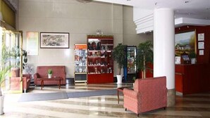 Una hall con una reception, un divano rosso, una libreria e un'imponente colonna.