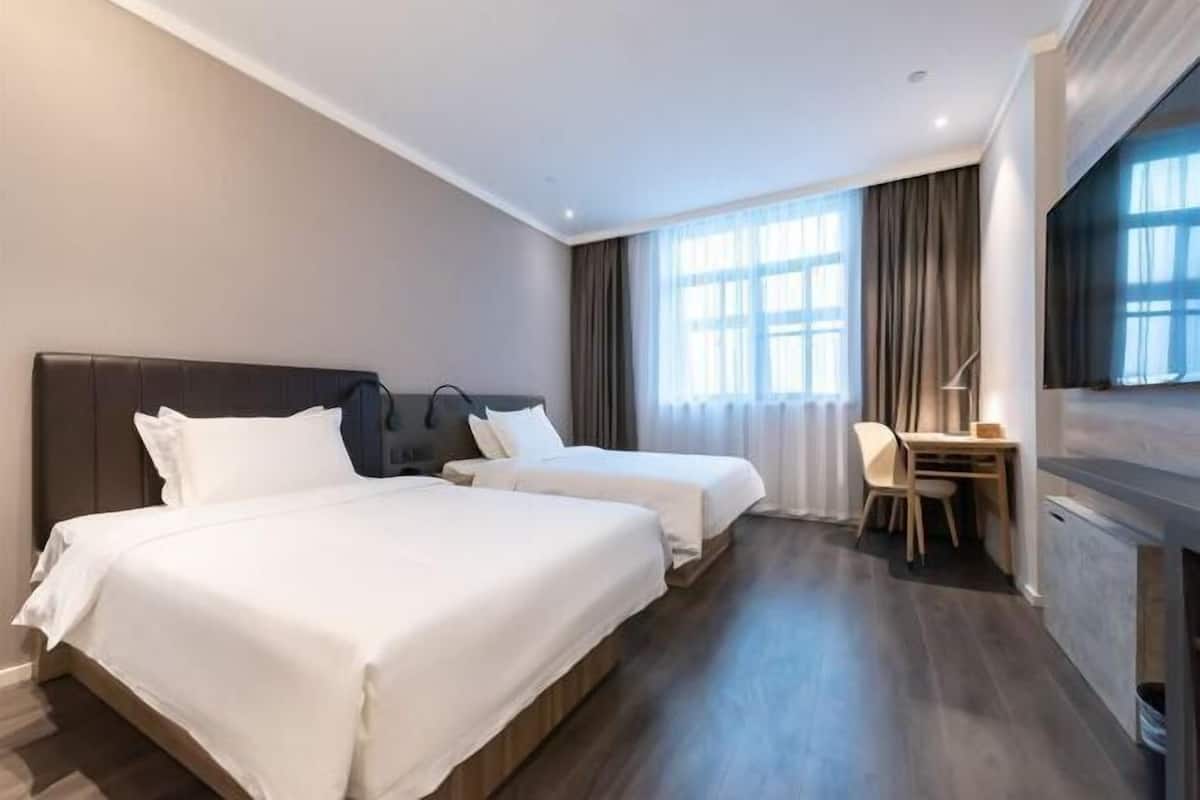 Una camera d'albergo con due letti, una scrivania, una sedia e un televisore.