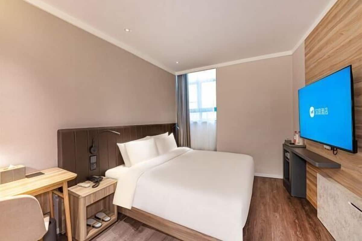 Una camera d'albergo con un letto, una scrivania, una TV e una finestra.