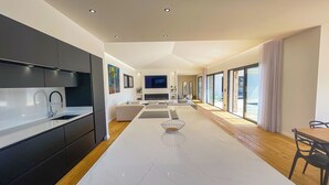 Una cocina moderna con armarios oscuros, encimera blanca y estufa integrada.