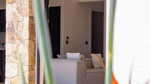 Una sala de estar moderna con un sofá y una mesa de centro, un pilar de piedra y una puerta que da a otra habitación.