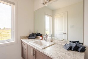 Bright bathroom with a spacious countertop, modern fixtures, and scenic window views.

