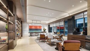 Un moderno vestíbulo de hotel con un amplio espacio de estar, una estación de café y una estantería.