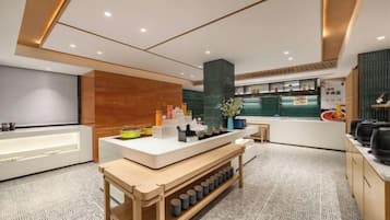 A modern hotel lobby with a reception desk, seating area, and a counter with food items.