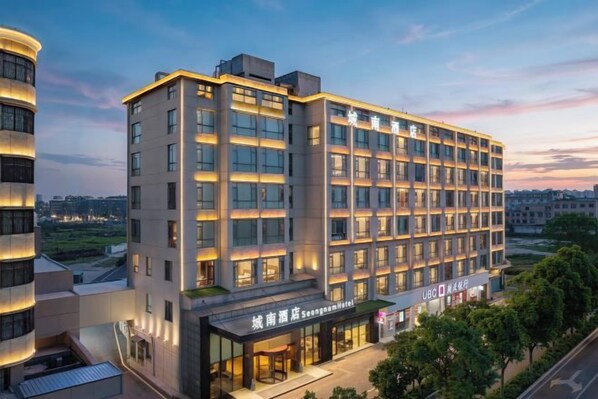 Un hotel de varios pisos con fachada moderna, ventanas grandes y una entrada visible con señalización.