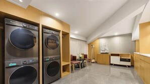 Habitación de hotel moderna con lavadora y secadora integradas, zona de comedor y un amplio ventanal.