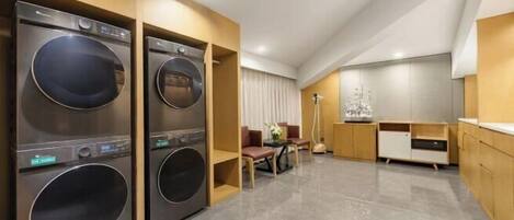 Quarto de hotel moderno com máquina de lavar e secar embutidas, espaço para refeições e uma janela grande.