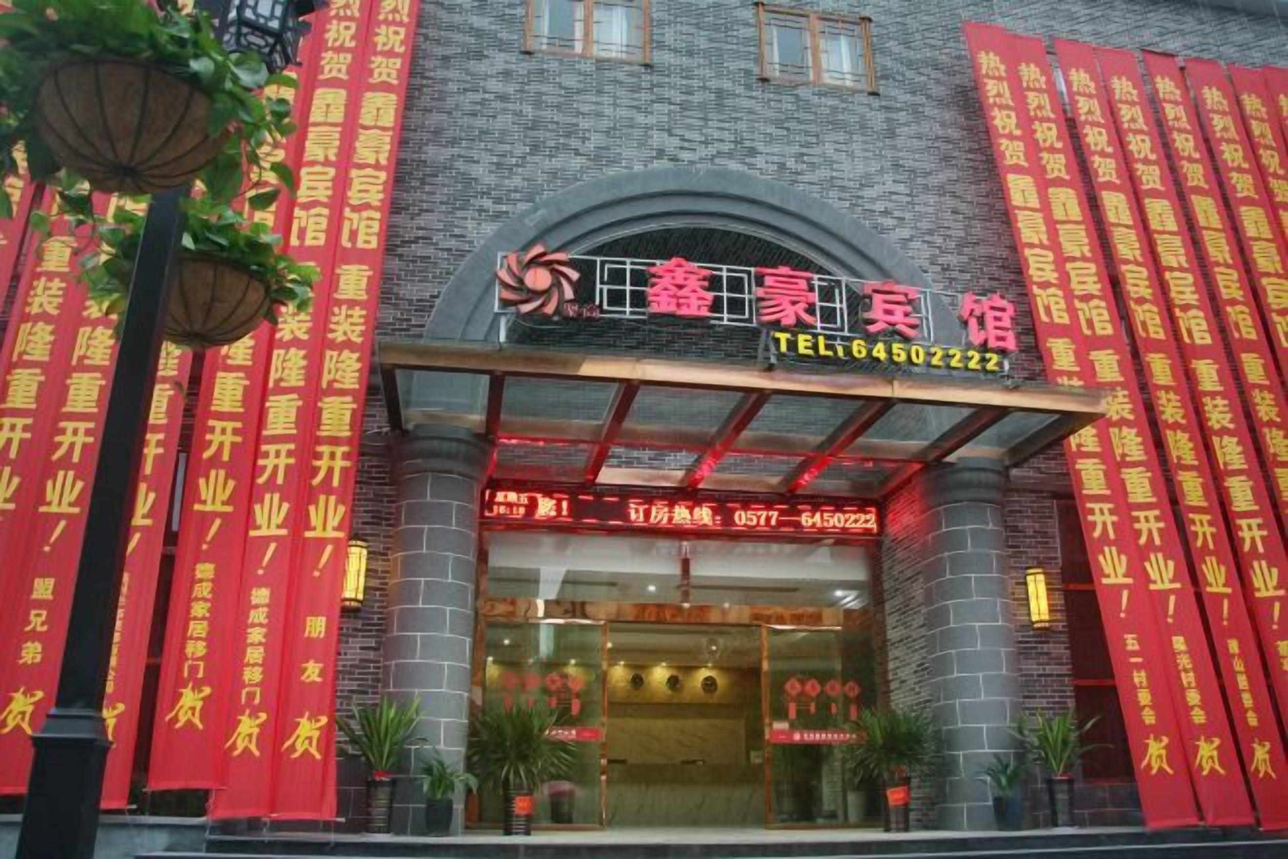 A hotel entrance with a prominent sign, a covered entrance, and red banners.