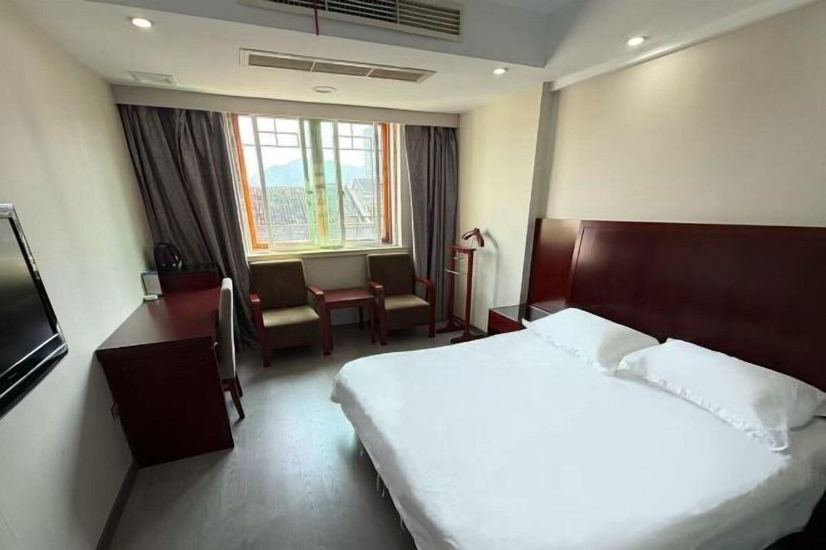 Une chambre d’hôtel équipée d’un lit, d’un bureau, d’une chaise, d’une télévision et d’une fenêtre avec des rideaux.