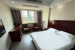 Une chambre d’hôtel équipée d’un lit, d’un bureau, d’une chaise, d’une télévision et d’une fenêtre avec des rideaux.