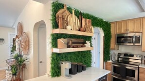 A kitchen with wooden cabinets, a microwave, an oven, and a green vertical garden wall.