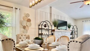 A dining room with a wooden table set for four, surrounded by upholstered chairs with button details.
