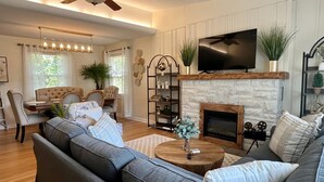 A living room with a fireplace, a television mounted above it, and a ceiling fan.
