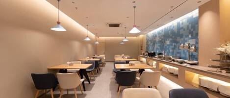 A modern restaurant interior with tables and chairs arranged for dining.