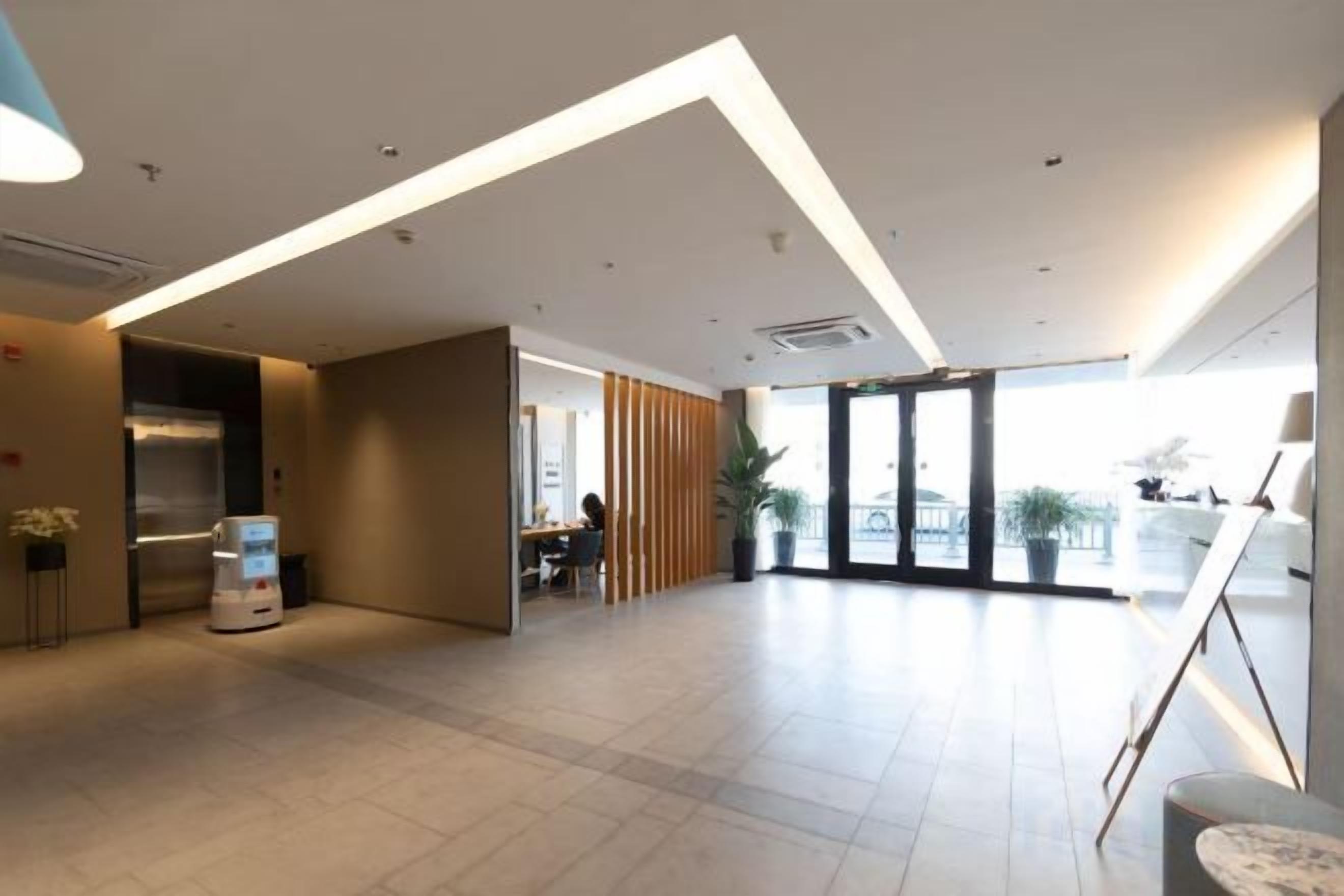 A spacious lobby with a reception desk, seating area, and a large window providing natural light.