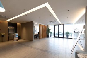 Eine großzügige Lobby mit einer Rezeption, einer Sitzecke und einem großen Fenster, das für natürliches Licht sorgt.