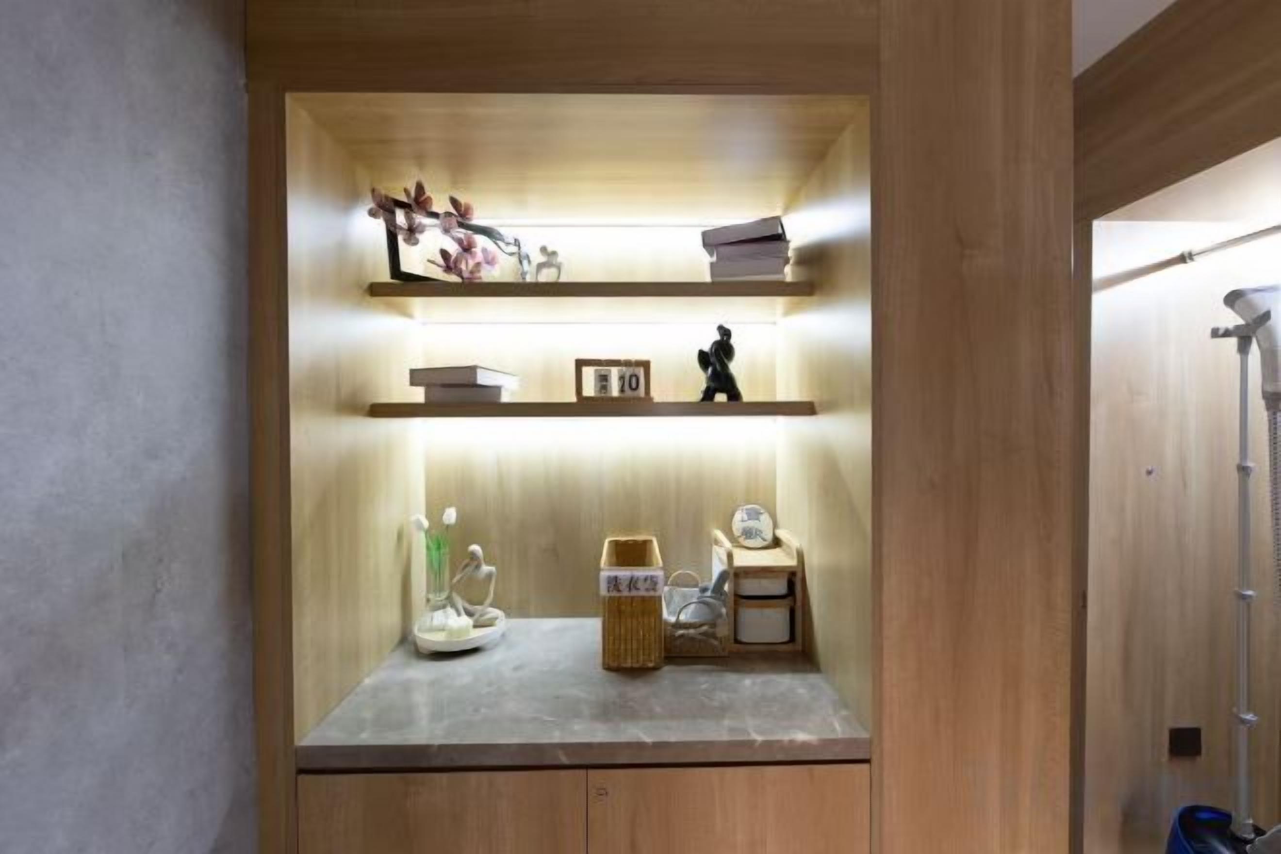 A wooden cabinet with shelves containing books, a figurine, and a small clock.