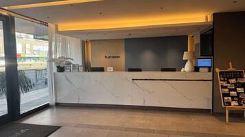 A hotel reception desk with a marble counter, a digital screen, and a sign that reads 'hummel'.
