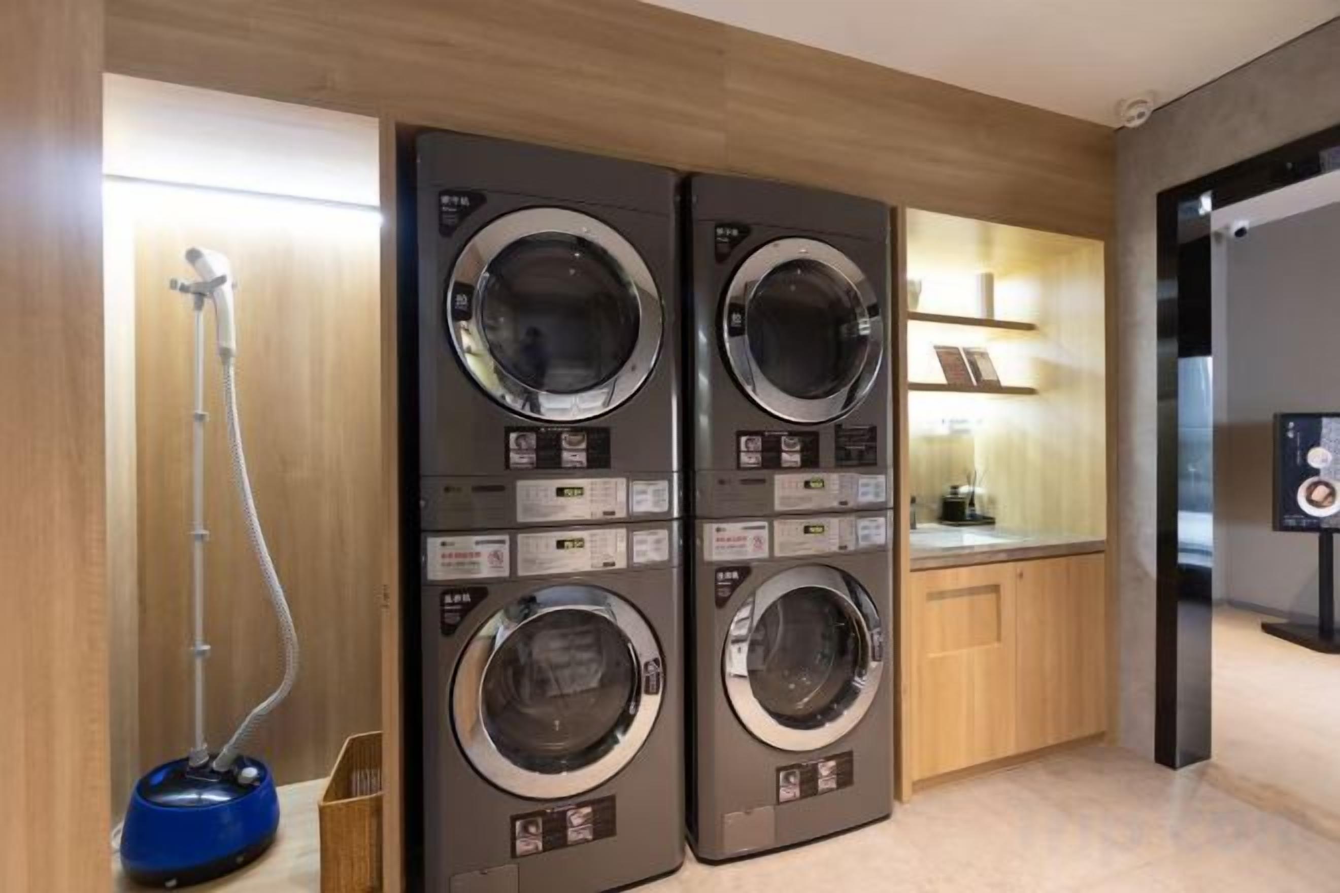 A laundry area with two stacked washing machines and a vacuum cleaner.